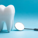 A white tooth next to a special dental mirror against a blue background in Dallas, TX