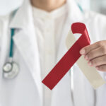 A Dallas dentist holds a red and beige ribbon to indicate oral cancer awareness