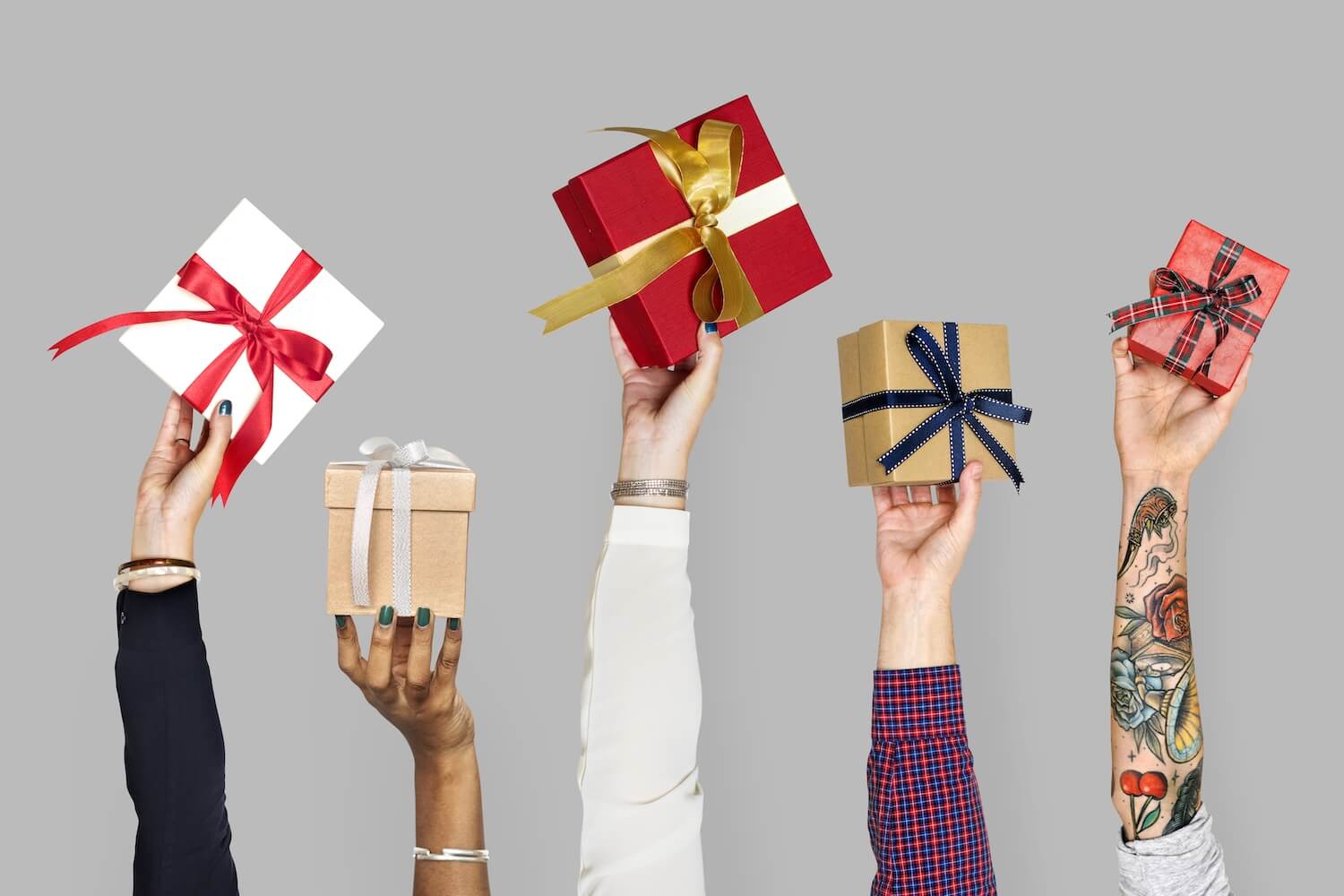 Several forearms shown with hands holding up gifts to symbolize gifting yourself a smile makeover